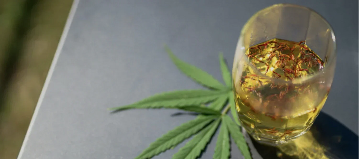 Cannabisblatt neben einem Glas mit Alkohol